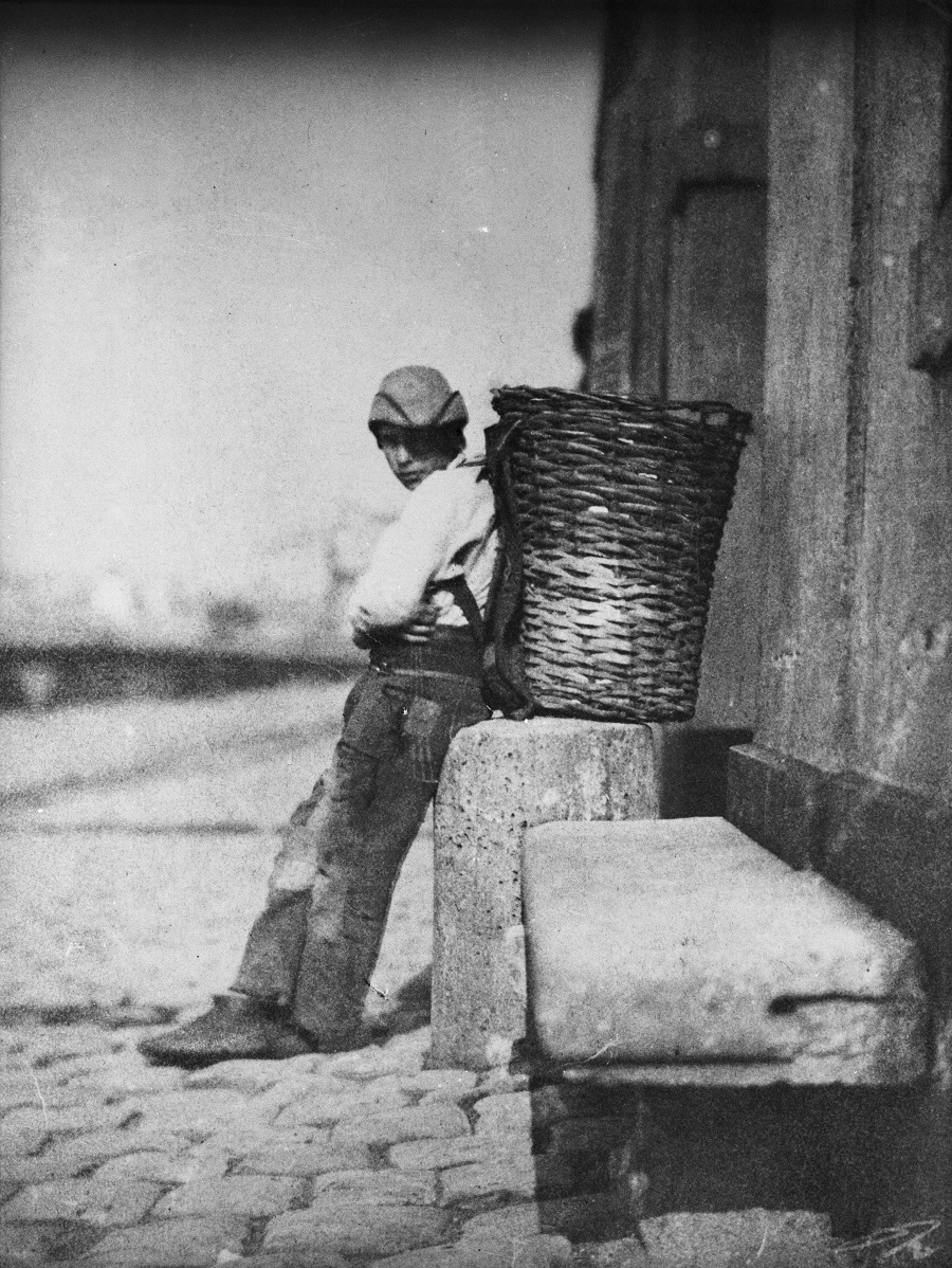 Le Petit Chiffonnier appuyé contre une borne devant le 21 quai Bourbon à Paris