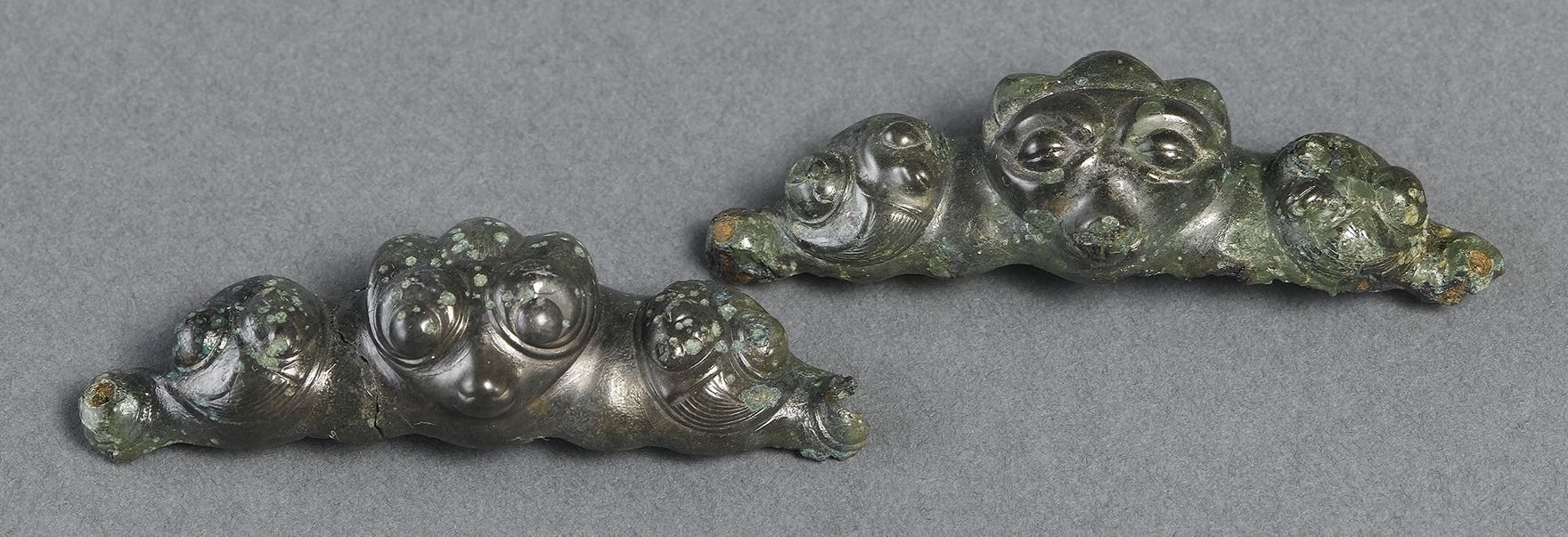 Deux appliques à masques, l’un les yeux mi-clos, l’autre les yeux ouverts