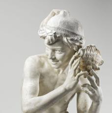 jeune garçon accroupi coiffé d'un bonnet écoutant une coquille