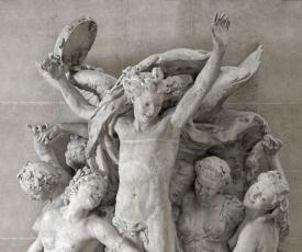 groupe sculpté avec un jeune homme tenant un tambourin entouré de jeunes femmes à demi-nues