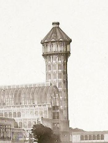 Photographie en noir et blanc d'une architecture en verre et fer et une tour
