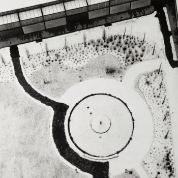 Photographie aérienne en plongée d'un parc, montrant une allée sinueuse, un rond-point et des massifs végétaux vus depuis un bâtiment en hauteur.