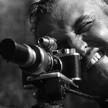 Photographe tenant un appareil Leica, le visage collé au viseur